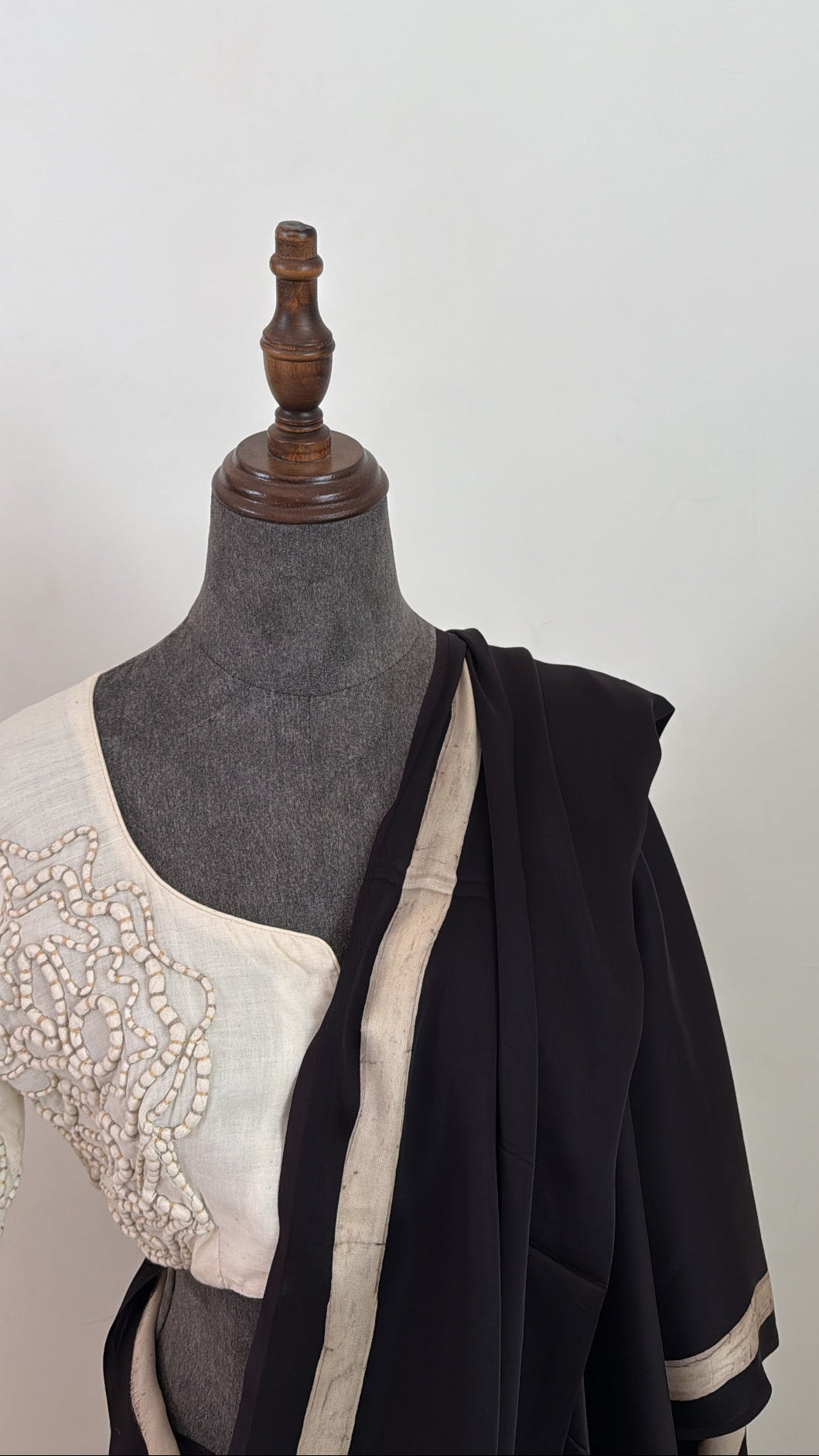 Mannequin wearing a black and white garment with a plain background